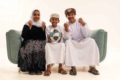 Omani Family in Traditional Attire Cheering with Football