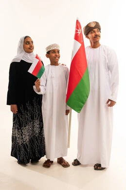 عائلة عُمانية تحمل العلم الوطني بالزي التقليدي