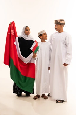 عائلة عمانية بالزي التقليدي تحمل علم سلطنة عمان