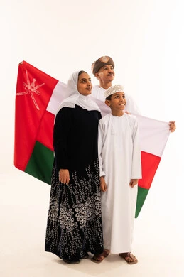 عائلة عمانية تحمل العلم الوطني بالزي التقليدي