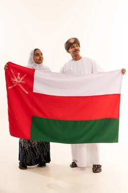 رجل وامرأة عُمانيان يحملان علم سلطنة عُمان