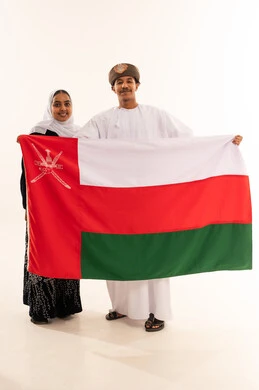 زوجان عمانيان يحملان العلم الوطني بالزي التقليدي