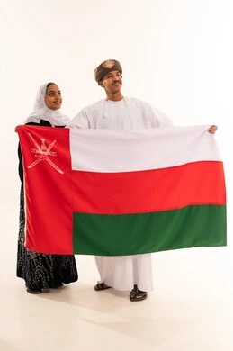 رجل وامرأة عمانيان يحملان علم سلطنة عمان الوطني