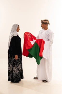 رجل وامرأة عمانيان يحملان علم سلطنة عمان
