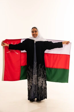 امرأة عُمانية تحمل العلم الوطني العُماني بخلفية بيضاء