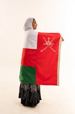 امرأة عمانية ملتفة بالعلم الوطني العماني