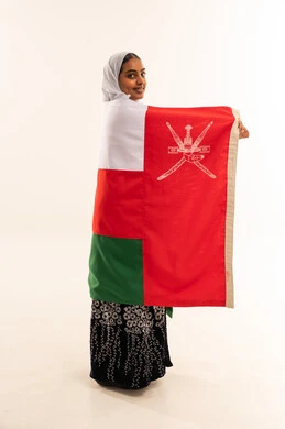 امرأة عُمانية تحمل العلم الوطني في استوديو