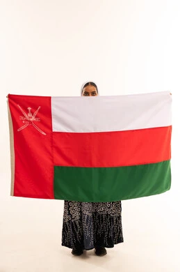 امرأة عُمانية تحمل علم سلطنة عُمان في استوديو