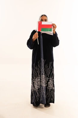 امرأة عُمانية بالعباءة تحمل علم سلطنة عُمان