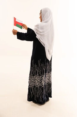 امرأة عُمانية بالعباءة تحمل علم سلطنة عُمان