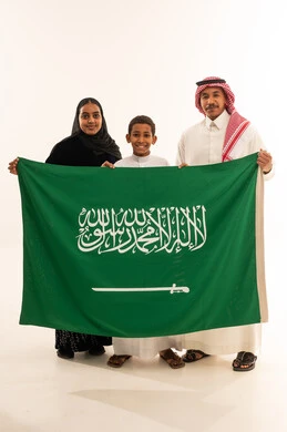 عائلة سعودية تحمل العلم الوطني بالزي التقليدي