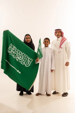 Saudi Family Holding National Flag in Traditional Attire