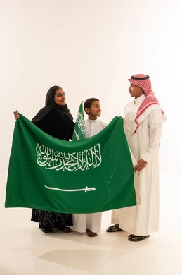 عائلة سعودية بالعلم الوطني والزي التقليدي