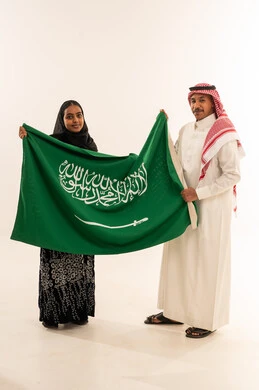 رجل وامرأة سعوديان يحملان العلم السعودي