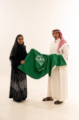 رجل وامرأة سعوديان يحملان علم السعودية
