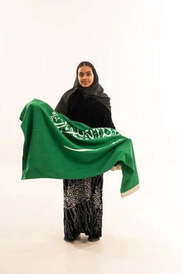 امرأة سعودية تحمل العلم الوطني على خلفية بيضاء