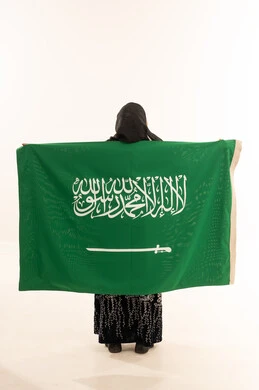امرأة سعودية تحمل العلم الوطني على خلفية بيضاء