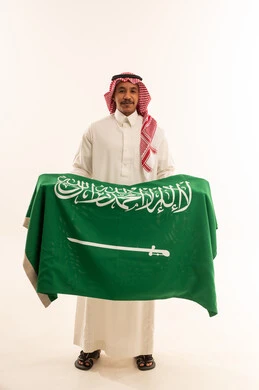 Saudi Man in Traditional Attire Holding Saudi Flag