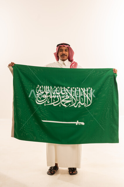 رجل سعودي يحمل علم المملكة العربية السعودية خلفية بيضاء