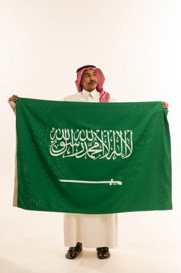 Saudi Man Holding Saudi Arabian Flag in Studio