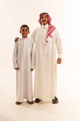 أب سعودي وابنه يرتديان الثوب التقليدي في الاستوديو