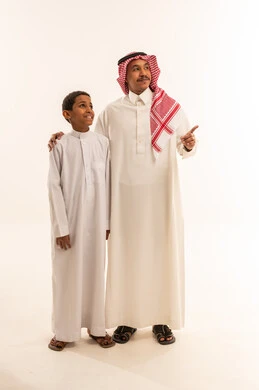 رجل وطفل سعودي بالزي التقليدي يشيران للأمام
