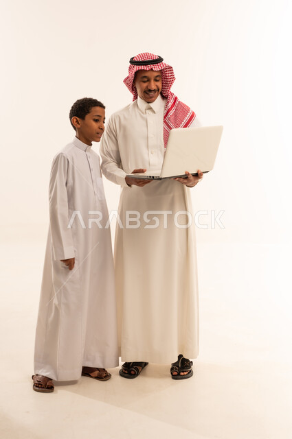 رجل سعودي وابنه يستخدمان الحاسوب المحمول