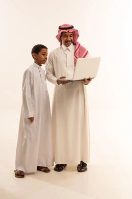 رجل سعودي وابنه يستخدمان الحاسوب المحمول