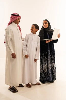 عائلة سعودية مع حاسوب محمول بالزي التقليدي