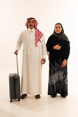 Saudi Couple in Traditional Dress with Travel Suitcase