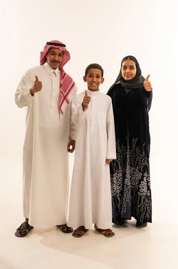 عائلة سعودية بالزي التقليدي تشير بعلامة الإعجاب