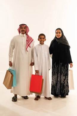 عائلة سعودية تحمل حقائب تسوق في استوديو
