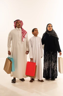 عائلة سعودية تحمل حقائب تسوق بالزي التقليدي