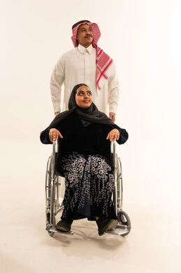 رجل وامرأة سعودية على كرسي متحرك خلفية بيضاء