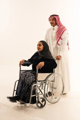 Saudi Man Assisting Woman in Wheelchair White Background