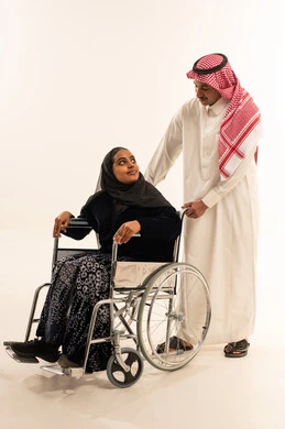 رجل سعودي يساعد امرأة في كرسي متحرك خلفية بيضاء