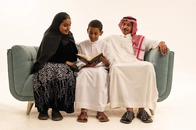 عائلة سعودية مع ابن يقرأ كتاباً على الأريكة