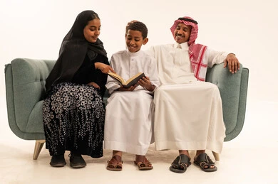 عائلة سعودية تقرأ كتاباً على الأريكة في الاستوديو