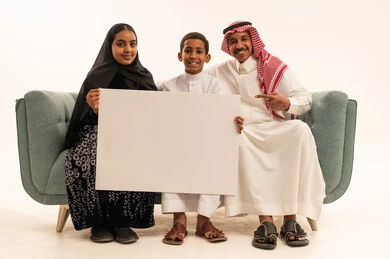 عائلة سعودية تحمل لوحة بيضاء فارغة في استوديو