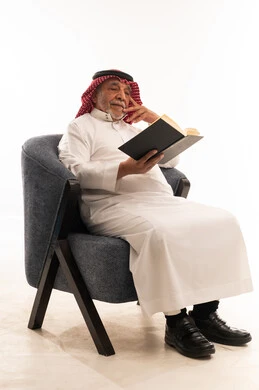 رجل سعودي مسن يقرأ كتاباً بالزي التقليدي