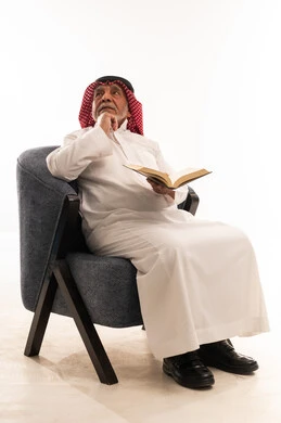 Elderly Saudi Man Reading Book in Armchair