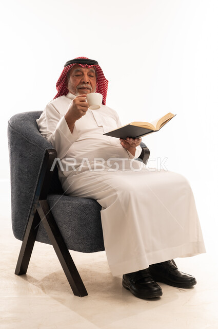 رجل سعودي مسن يقرأ كتاباً ويشرب القهوة