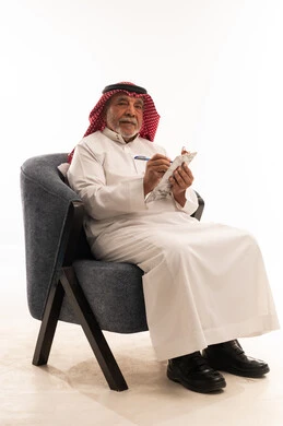 رجل سعودي مسن مع لوحة كتابة بخلفية بيضاء