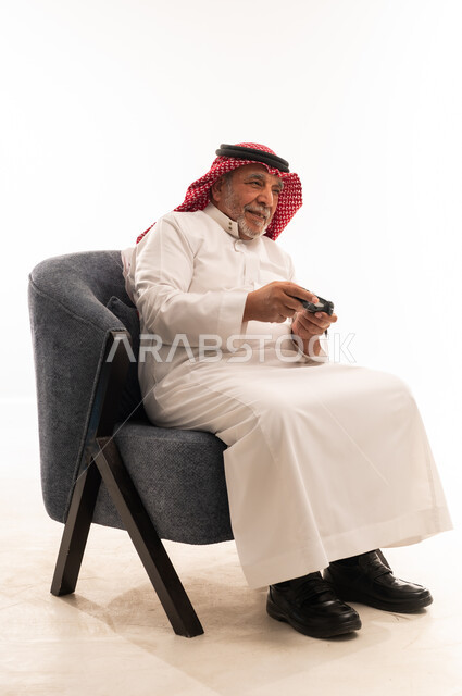 رجل سعودي مسن بالزي التقليدي يمسك جهاز تحكم