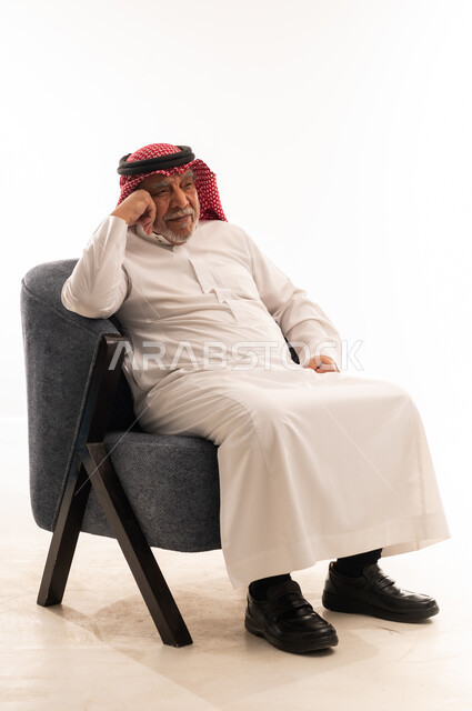 رجل سعودي مسن يجلس على كرسي في الاستوديو