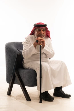 رجل سعودي مسن يجلس متكئا على عصا