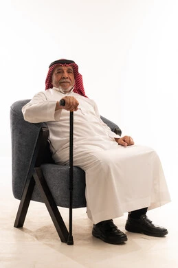 رجل سعودي مسن مع عصا مشي بخلفية بيضاء