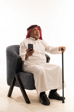 رجل سعودي مسن يحمل هاتفاً ذكياً وعصا مشي