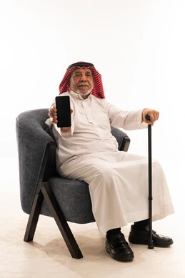 رجل سعودي مسن يحمل هاتف ذكي بخلفية بيضاء
