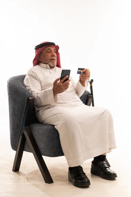 Saudi Elderly Man Using Credit Card on Smartphone